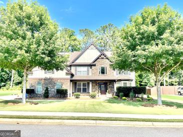 Charming two-story home with stone accents, manicured lawn, and mature trees offering shade and curb appeal at 145 Seawright Dr, Fayetteville, GA 30215