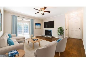 Cozy living room features a ceiling fan, fireplace, hardwood floors, and ample natural light at 503 Countryside Se Pl, Smyrna, GA 30080