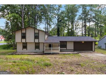 Two-story home featuring neutral siding, covered porch, attached garage, and surrounded by mature trees at 770 Four Winds Ln, Jonesboro, GA 30238