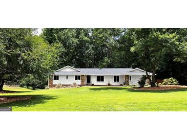 Charming ranch home featuring a well-manicured lawn, stone accents, a new roof, and lush landscaping at 1035 Hunterhill Dr, Roswell, GA 30075