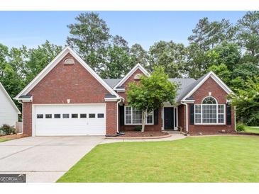 Charming brick home featuring manicured lawn, mature landscaping, and a two-car garage at 192 Sandhurst Ct, Suwanee, GA 30024