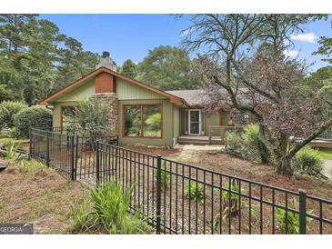 Charming single-story home with a stone chimney, large windows, and a well-maintained front yard at 6220 Petersburg Rd, Fairburn, GA 30213