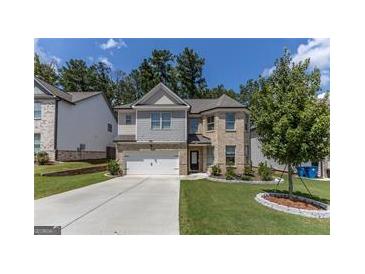 Charming two-story home featuring a manicured lawn, brick accents, a two-car garage, and a neatly landscaped yard at 2004 Brittlebank Ln, Lawrenceville, GA 30043