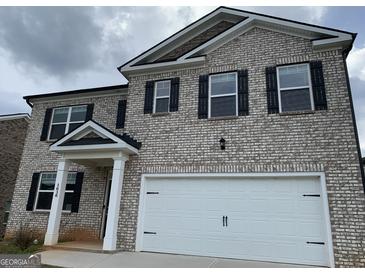 Beautiful two-story home featuring a brick exterior, an attached garage, and a covered entryway at 1636 Jersey Dr, Stockbridge, GA 30281