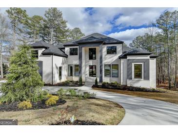 Stunning two-story brick home with a manicured lawn, a circular driveway, and modern gray accents at 4090 Sandy Lake Dr, Lithonia, GA 30038