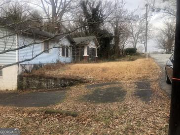Modest home featuring blue siding, a partially screened porch, and a long driveway leading to the street at 702 Emily Nw Pl # 0, Atlanta, GA 30318