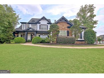Stunning two-story home with a manicured lawn, stone and siding details, and a welcoming front porch at 383 Beaumont Farms Dr, Sharpsburg, GA 30277