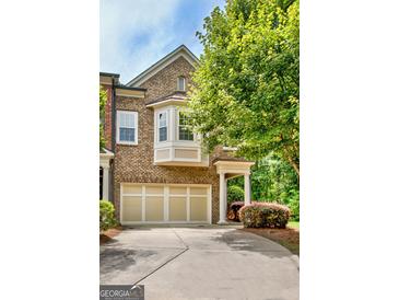 Inviting brick townhome featuring a two-car garage, bay window and covered front porch amidst lush landscaping at 50 Star Spangled Ln, Peachtree City, GA 30269