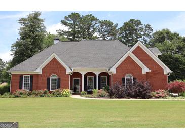 Charming red brick home with a well-manicured lawn and mature landscaping at 405 Mallory Cir, Loganville, GA 30052