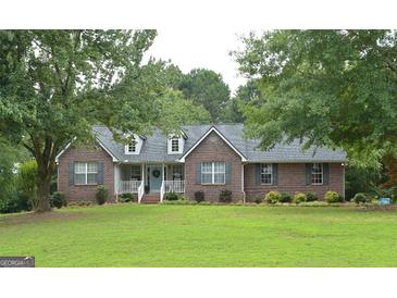 Charming one-story brick home featuring a well-manicured lawn and complemented by lush, mature trees at 219 Brown Branch Rd, Locust Grove, GA 30248