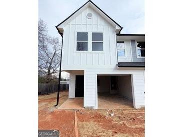 New construction features white siding, black trim, an open garage and covered entrance at 11594 E Lovejoy Rd # 1, Hampton, GA 30228