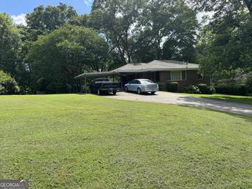 Charming brick home featuring a carport and a well-manicured front yard with mature trees at 537 Elizabeth Sw Ln, Mableton, GA 30126