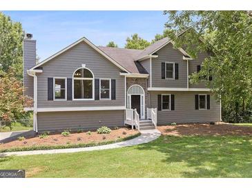 Charming two-story home featuring a landscaped yard, inviting entrance, and neutral-colored siding with black shutters at 1400 Land Rd, Canton, GA 30114