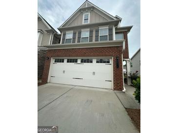 Charming brick home featuring a two-car garage with stylish carriage door and well-manicured lawn at 2060 Lanier Harbor Pt, Buford, GA 30518