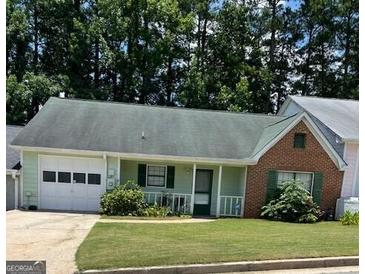 Charming one-story home featuring a well-maintained lawn, attached garage, and inviting front porch at 207 Oak N Cir, Stockbridge, GA 30281