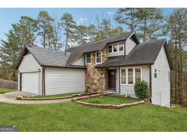 Charming home featuring stone accents, a two-car garage, a lush lawn, and mature trees in a serene setting at 5368 Nw Stafford Nw Dr, Lilburn, GA 30047