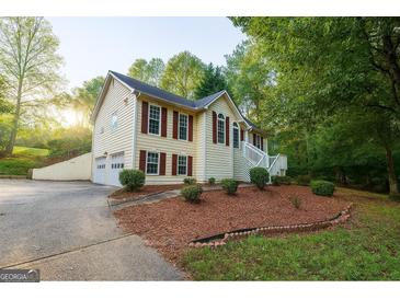 Charming two-story home with wood siding, a well-manicured lawn, and lush landscaping at 1858 Mcconnell Rd, Grayson, GA 30017