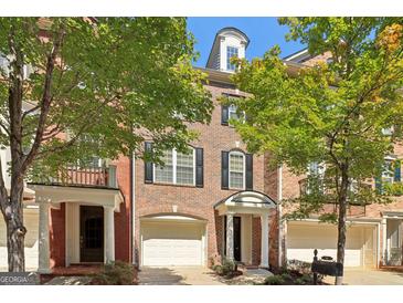 Charming brick townhouse with a one-car garage, black shutters, and mature trees at 56 American Walk, Peachtree City, GA 30269