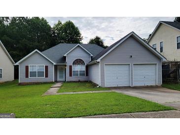 Charming gray home featuring a two-car garage and a well-manicured front lawn at 5502 Sapphire Cir, Ellenwood, GA 30294
