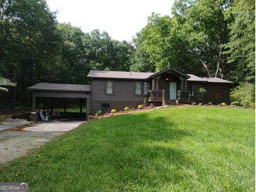 Charming single-story home with a lush lawn and covered carport nestled among mature trees at 4023 Anvil Block Rd, Ellenwood, GA 30294