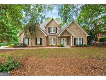 Charming brick home featuring manicured landscaping, black shutters and inviting front porch at 595 Mcgarity Dr, Mcdonough, GA 30252