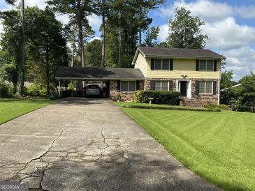 Traditional two-story home with yellow siding, black shutters, a carport, and a well-maintained front lawn at 529 Valley Woods Se Cir, Conyers, GA 30094