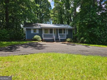 Charming one-story home with a metal roof, inviting porch, and a spacious driveway, surrounded by lush greenery at 602 Mccurdy Rd, Villa Rica, GA 30180