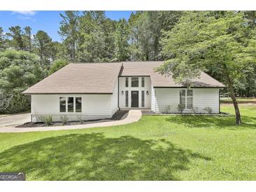 Inviting white home with a well-manicured lawn, complemented by mature trees and tasteful landscaping at 205 Shadowood Ln, Peachtree City, GA 30269