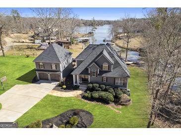Aerial view of a gray house featuring a well-manicured lawn and lake access on a sunny day at 50 Birch Rd, Covington, GA 30014