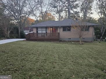 Charming brick home featuring a spacious front yard and wooden deck, perfect for outdoor enjoyment at 655 Shellnut Dr, Forest Park, GA 30297