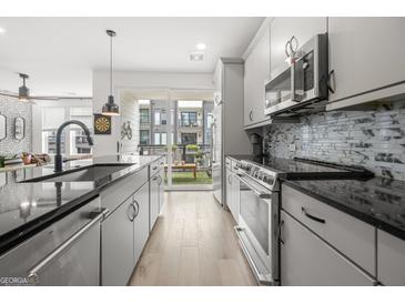 Modern kitchen with stainless steel appliances, granite countertops, and access to the outdoor balcony at 383 Pratt Dr # 506, Atlanta, GA 30315