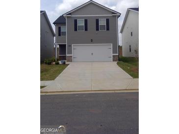Charming two-story home featuring a two-car garage and a well-manicured front lawn at 11899 Aukerman Way, Hampton, GA 30228