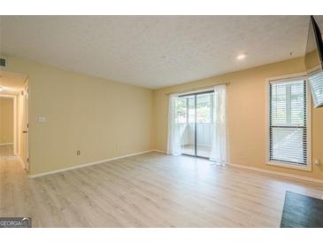 Bright living room featuring light-colored floors, sliding glass doors to a balcony, and a window letting in natural light at 1102 Wynnes Ridge Cir, Marietta, GA 30067