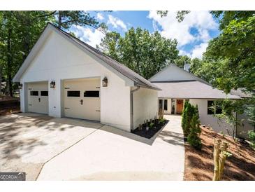 Beautiful home exterior with a two-car garage, manicured landscaping, and a charming pathway at 145 Mount Shasta Ln, Johns Creek, GA 30022