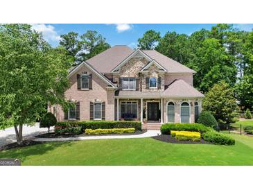 Stunning brick and stone home featuring manicured landscaping and a lush green lawn at 2230 Cambridge Hill Ct, Dacula, GA 30019