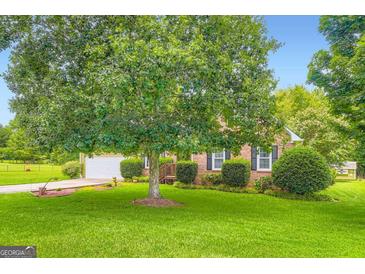 Well-maintained lawn and mature tree enhance the curb appeal of this brick home at 180 Moseley Crossing Dr, Stockbridge, GA 30281