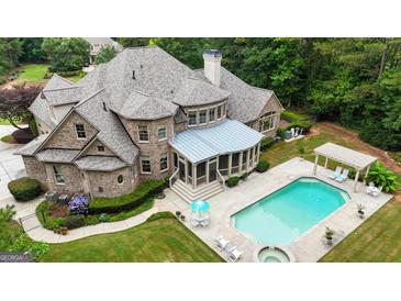 Aerial view of a brick home with a screened porch, pool, spa, pergola and outdoor seating at 310 Westbourne Dr, Tyrone, GA 30290