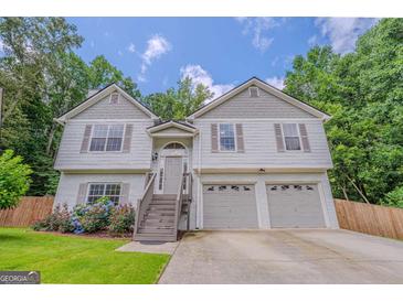 Inviting two-story home featuring a two-car garage and a well-maintained front yard with vibrant flowers at 3781 Deercreek Dr, Powder Springs, GA 30127