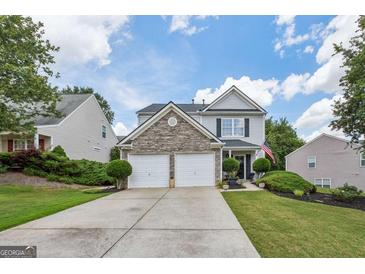 Charming two-story home with a two-car garage, stone accents, manicured lawn and inviting curb appeal at 142 Holly Mill Village Dr, Canton, GA 30114