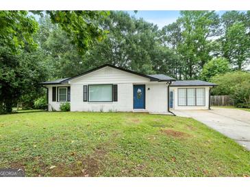 Charming single-story home with a white brick exterior, blue door, and a well-manicured front lawn surrounded by mature trees at 1694 Pheasant Dr, Atlanta, GA 30238