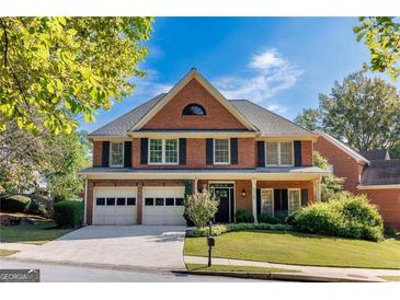 Charming two-story brick home features a manicured front lawn, two-car garage, and classic architectural details at 4729 Woodland Brook Se Ct, Atlanta, GA 30339