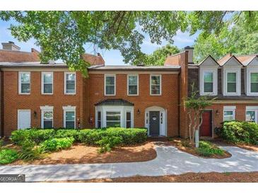 Charming brick townhome featuring mature trees and landscaping, creating a welcoming curb appeal at 4113 Ashford Green Dr, Duluth, GA 30096