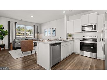 Bright open-concept living space features modern kitchen with stainless appliances and adjacent cozy living area at 2810 Georgia Aster Nw Way # 6, Atlanta, GA 30318