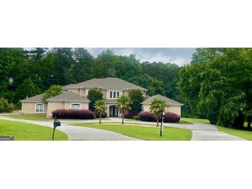 An elegant two-story home featuring a circular driveway, lush lawn, decorative shrubs and landscaping and a beautiful facade at 345 Peaceful Way, Fayetteville, GA 30214