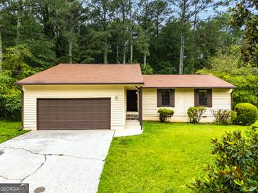 Charming one-story home with a brown roof, green lawn, and attached garage in a wooded setting at 9719 Dixon Industrial, Jonesboro, GA 30236