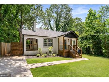 Charming renovated bungalow with white painted brick, dark trim, a new roof, a lovely front porch, and lush landscaping at 345 Adelle Se St, Atlanta, GA 30315