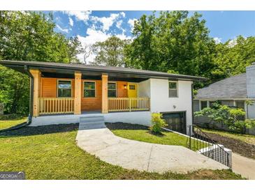 Charming home with a wood-accented porch, yellow door, painted brick, and a well-manicured front lawn at 1400 North Avenue Nw, Atlanta, GA 30318