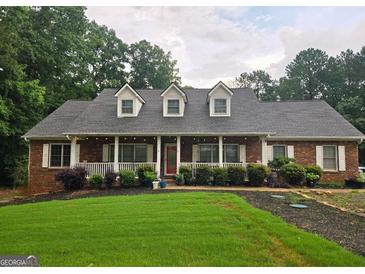 Charming brick home featuring a covered porch with dormer windows and lush landscaping at 79 The Farm Rd, Mcdonough, GA 30252