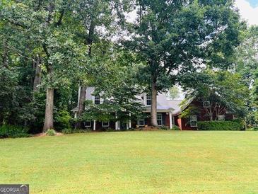 Charming brick home nestled among mature trees with a sprawling green lawn at 149 Crown Oaks Dr, Stockbridge, GA 30281