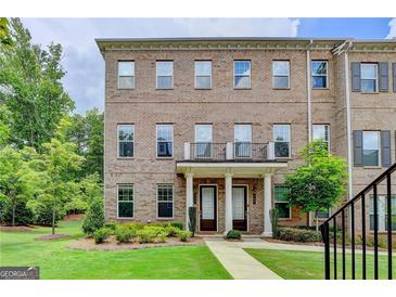 Brick townhome featuring a well-manicured lawn, covered entrance and second story balcony at 711 Topsail Ln, Alpharetta, GA 30005